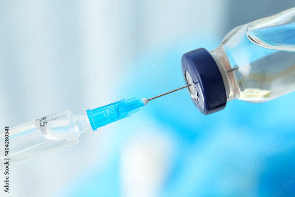 Filling syringe with vaccine on blurred background, closeup Filling syringe with vaccine on blurred background, closeup
