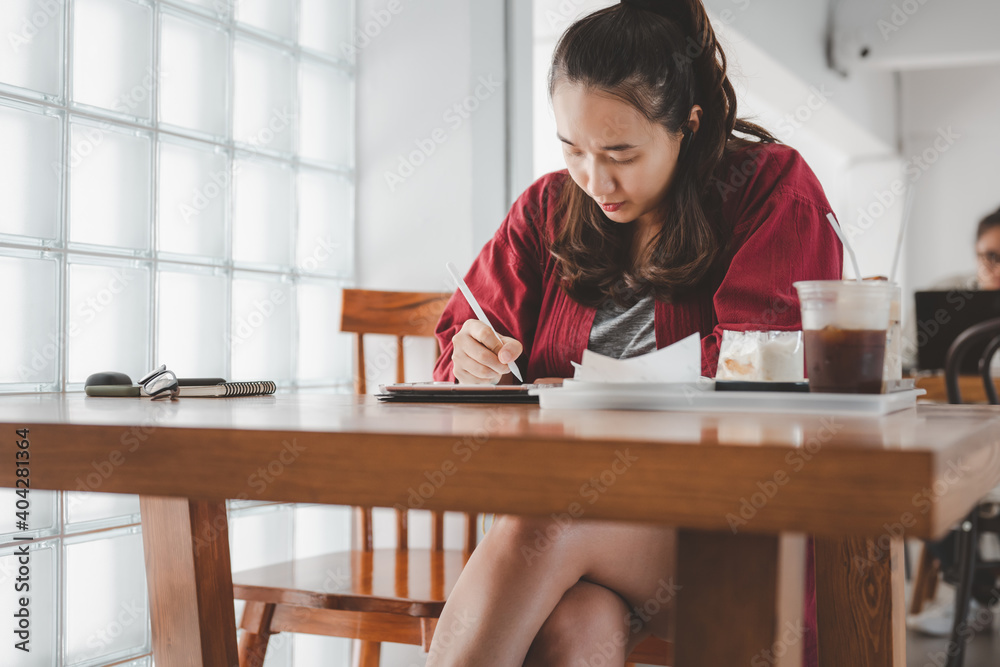 smart Asian woman copywriter working freelance project in modern cafe. Businesswoman using smartphone and tablet, searching information on website. Successful business. Online training courses concept