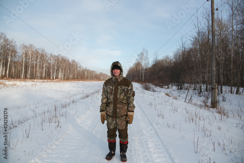 A logger saws a tree in the forest in winter, in Russia for firewood