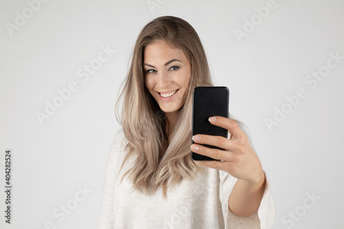 woman having shooting self portrait on front camera of smart phone cellphone