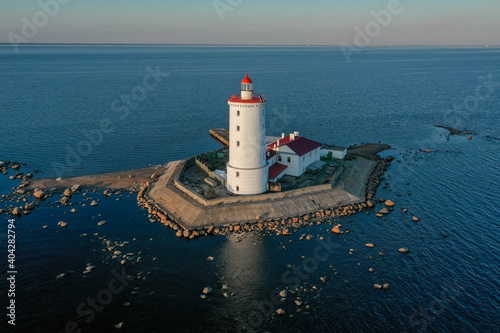 Panoramic aerial view of the Tolbukhin lighthouse. Artificial rocky island in the Gulf of Finland. The oldest Russian lighthouse. Baltic Sea. Stony coast. Summer day. Blue sky.