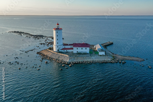 Panoramic aerial view of the Tolbukhin lighthouse. Artificial rocky island in the Gulf of Finland. The oldest Russian lighthouse. Baltic Sea. Stony coast. Summer day. Blue sky.