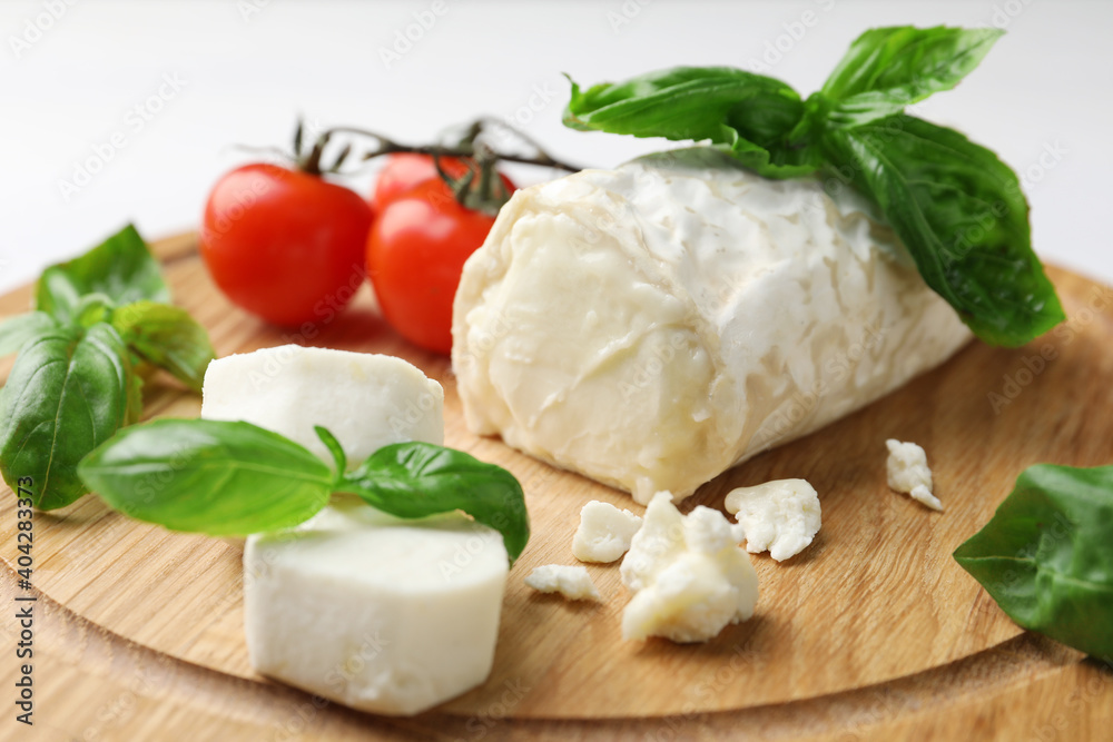 Delicious goat cheese with tomatoes and basil on wooden board, closeup Delicious goat cheese with tomatoes and basil on wooden board, closeup