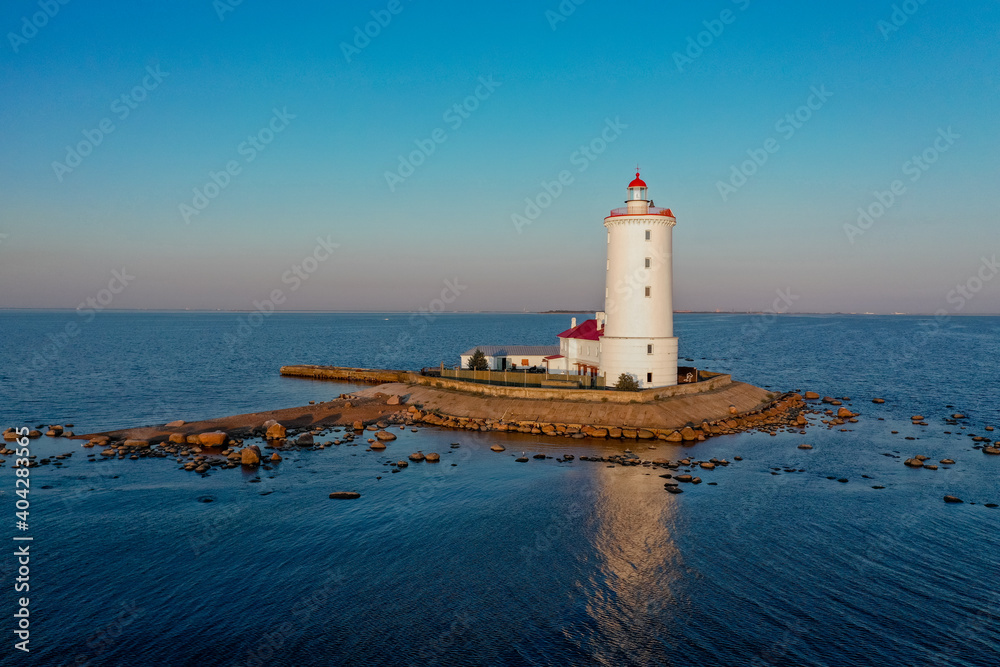 Panoramic aerial view of the Tolbukhin lighthouse. Artificial rocky island in the Gulf of Finland. The oldest Russian lighthouse. Baltic Sea. Stony coast. Summer day. Blue sky.