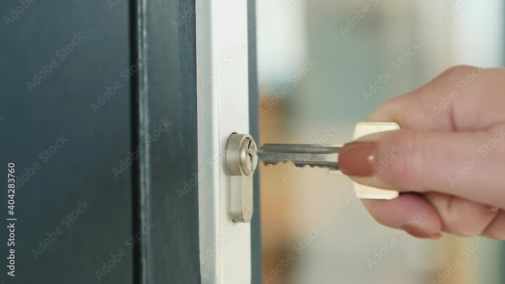 The woman slowly inserts the key into the keyhole of the front door The woman slowly inserts the key into the keyhole of the front door