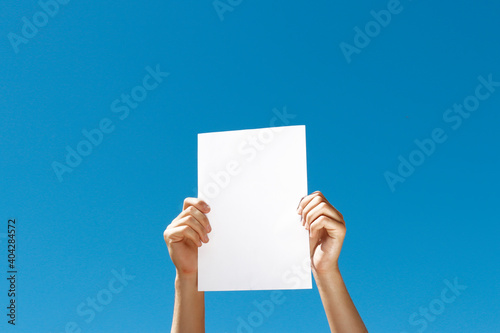 blank sheet of paper in hands on blue background