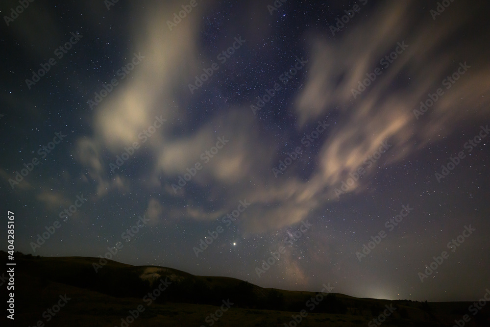 Bright stars in the night sky with clouds.
