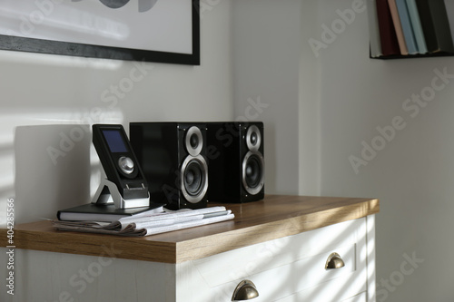Modern powerful audio speakers and remote on chest of drawers indoors