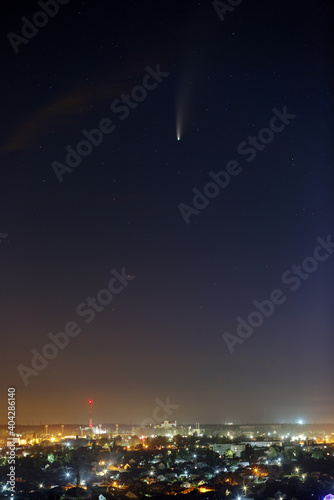 Bright comet C / 2020 F3 (NEOWISE) in the starry night sky. Deep space object over a city with bright street lighting.