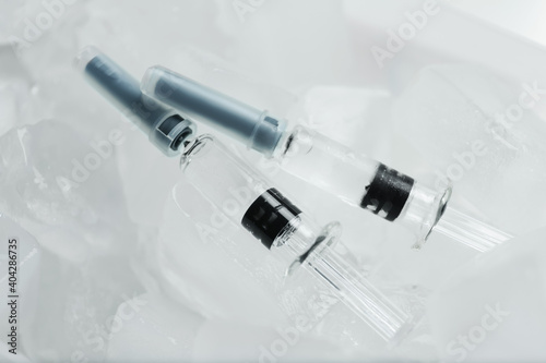 Syringes with COVID-19 vaccine on ice cubes