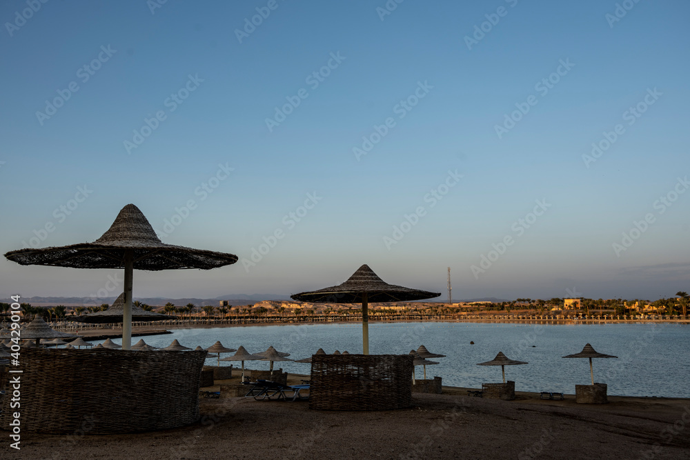 deserted beach with wicker umbrellas and lack of vacationers against the blue sky