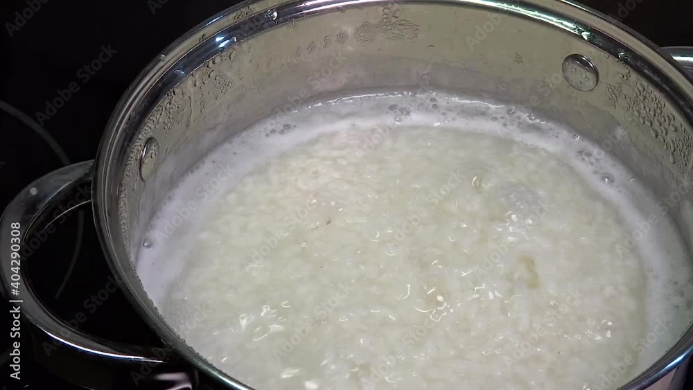 Rice is cooked in a saucepan. Cooking porridge for breakfast. Side dish for main courses, lunch. Boiling water and boiled grains close-up. Rice is cooked in a saucepan. Cooking porridge for breakfast. Side dish for main courses, lunch. Boiling water and boiled grains close-up.