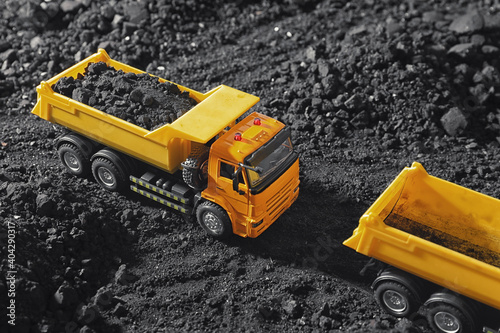 Toy tipper trucks with coal in field