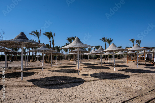 deserted beach with wicker umbrellas and lack of vacationers against the blue sky