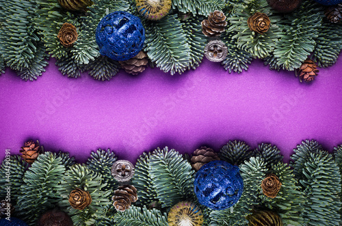 Purple Christmas background. Spruce twigs with New Year s toys  cones.