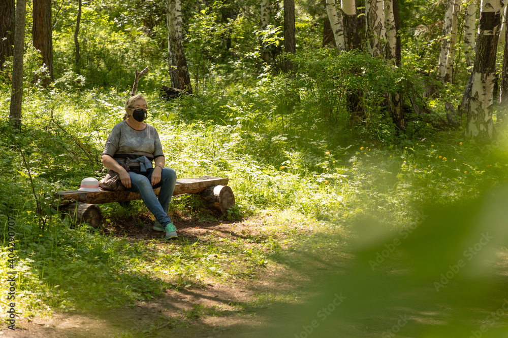 Middle-aged woman in a protective mask walks in the park