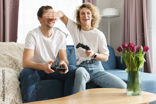 Couple with a gamepads are playing video game console at home