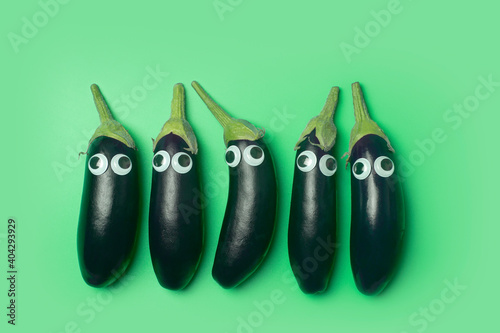 Kids food concept. Eggplant with eyes on a colored green background. Funny vegetables and food for kids photo