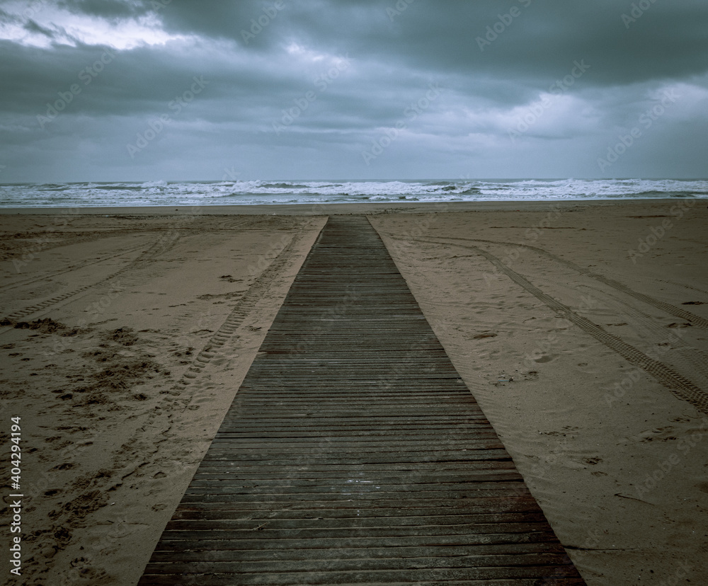 Wooden walkway on the beach on a rainy winter day.