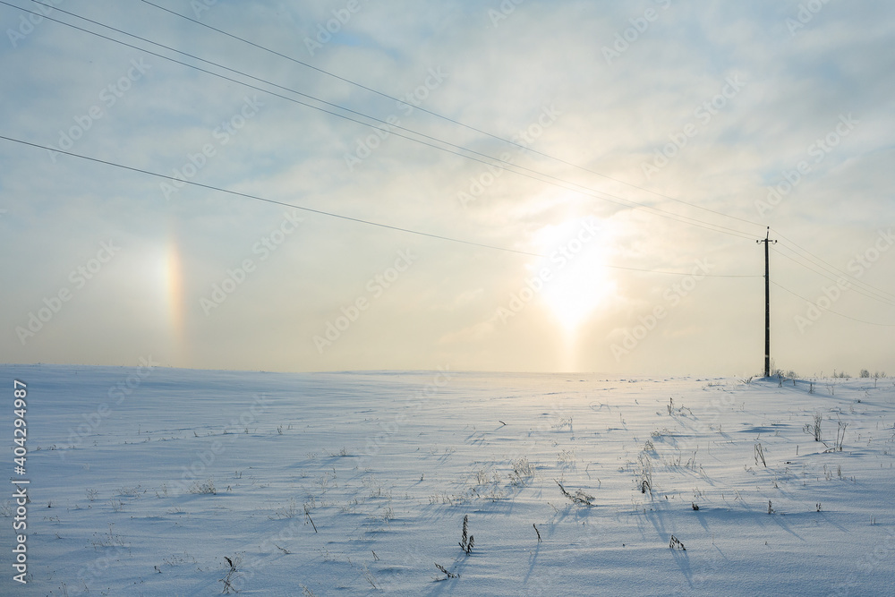 Sunrise and halo phenomena on a winter morning in a snowy field