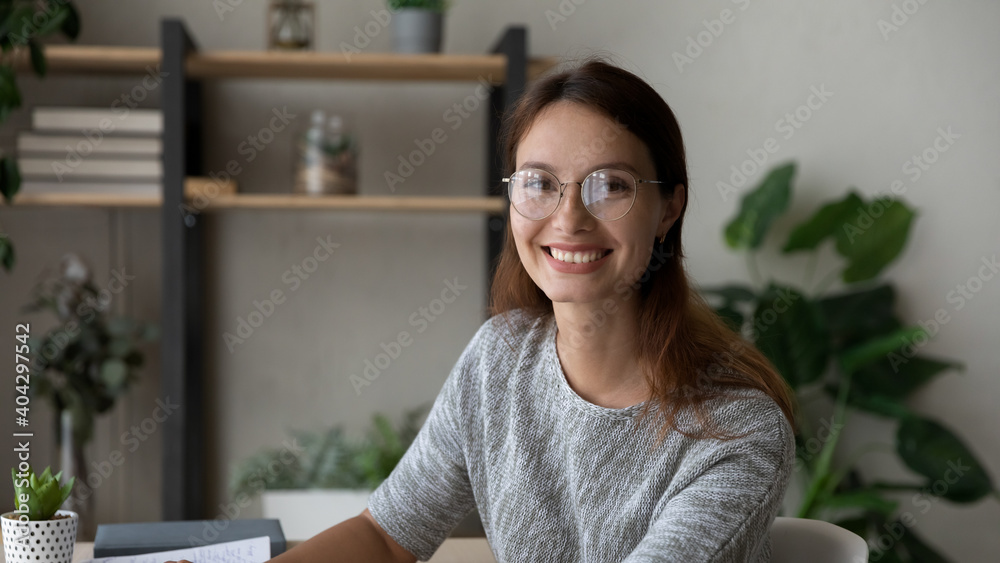 Wide banner view portrait of smiling millennial woman in glasses study at home office. Happy young Caucasian 20s female employee or student in spectacles look at camera posing in quality eyewear. Wide banner view portrait of smiling millennial woman in glasses study at home office. Happy young Caucasian 20s female employee or student in spectacles look at camera posing in quality eyewear.