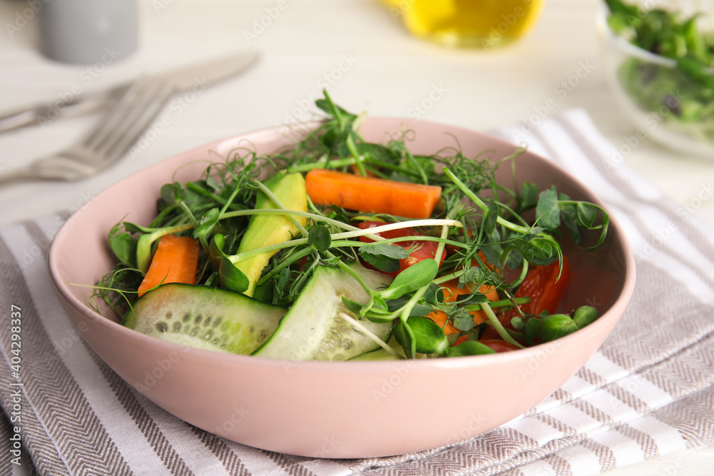 Salad with fresh organic microgreen in bowl on white table, closeup Salad with fresh organic microgreen in bowl on white table, closeup