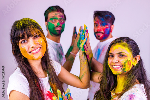 four indian students painted in colors celebrating holi festival in studio white isolate background hogh five photo