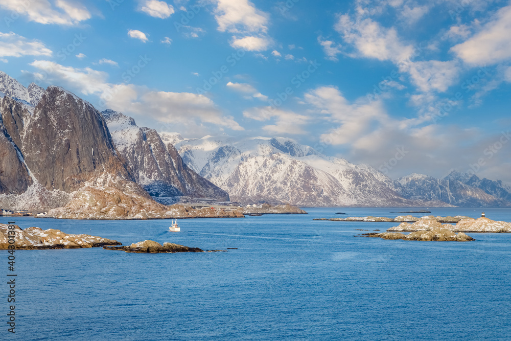 Lofoten islands, Norway. Amazing winter landscape with fjord, rocky coastline, mountains covered with snow in the background. Travel Norway.