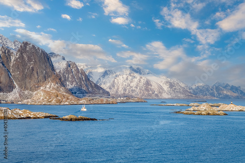 Lofoten islands, Norway. Amazing winter landscape with fjord, rocky coastline, mountains covered with snow in the background. Travel Norway.