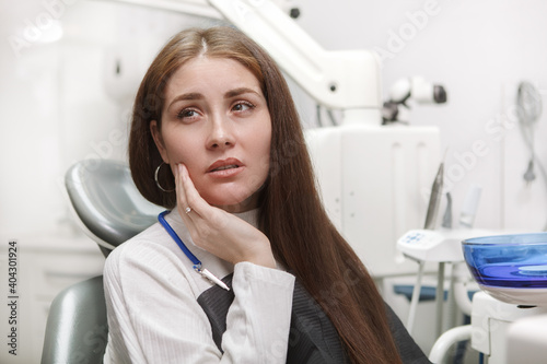 Close up of a woman suffering from toothache  sitting in dental chair at the clinic