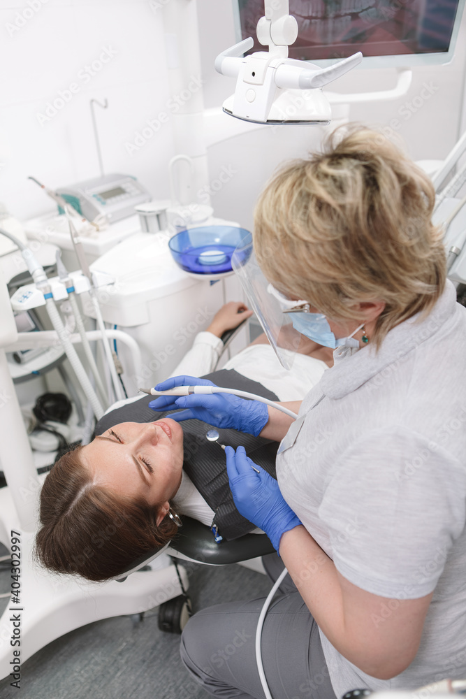 Vertical shot of a female patient getting dental treatment by experienced dentist Vertical shot of a female patient getting dental treatment by experienced dentist