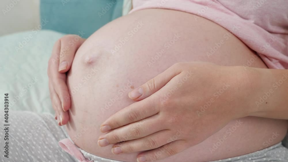 CLoseup photo of pregnant woman lying on bed at hospital and holding hands on her big belly. Concept of expecting baby, pregnancy and healthcare. CLoseup photo of pregnant woman lying on bed at hospital and holding hands on her big belly. Concept of expecting baby, pregnancy and healthcare.
