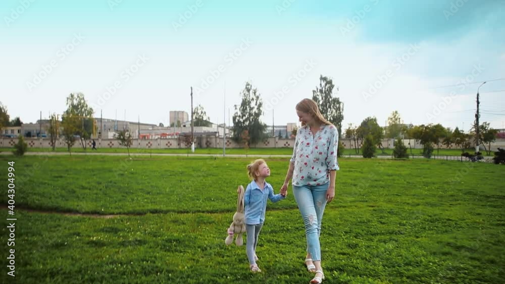 Mom and daughter are walking on the green grass. happy family concept. Mom and daughter are walking on the green grass. happy family concept.