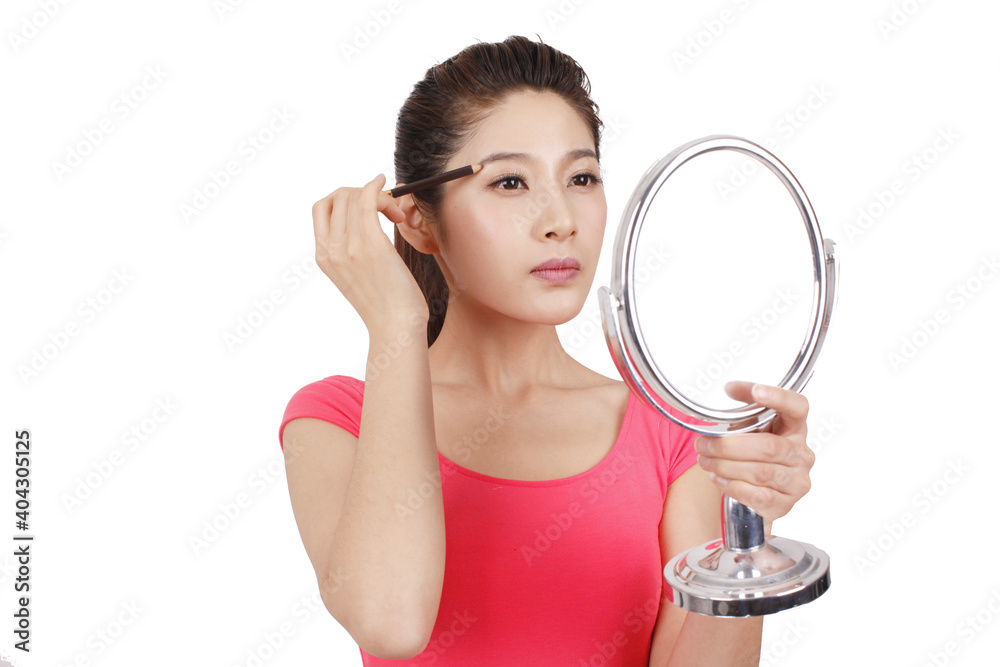 Young woman in pink dress holding a mirror,applying make-up Young woman in pink dress holding a mirror,applying make-up