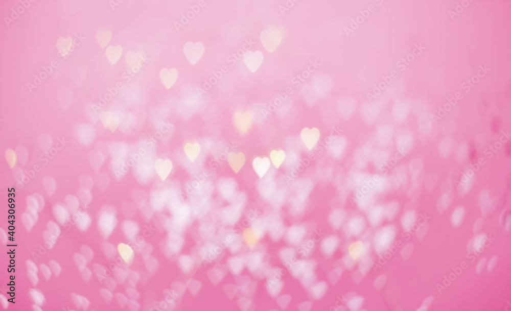 Yellow and pink bokeh in the shape of hearts on a pink background copy space. Valentine background