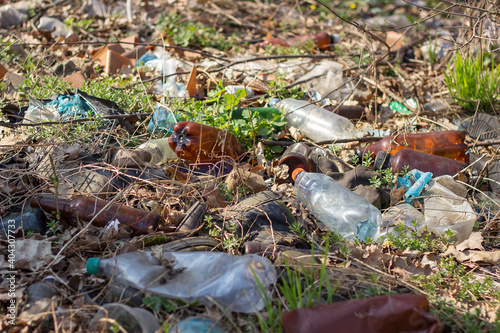 primroses snowdrops bloom in early spring in the sun under debris and plastic. Ecology. Environmental pollution.