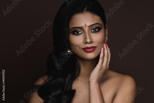 Portrait of Indian woman with beautiful makeup and hairstyle on brown background