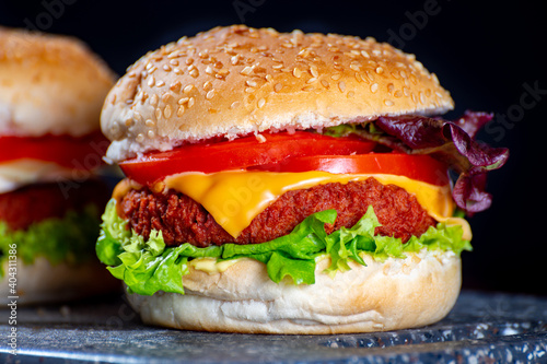 Tasty vegetarian food, homemade cheeseburgers made from plant based soya meat with cheese, onion, green lettuce and tomatoes