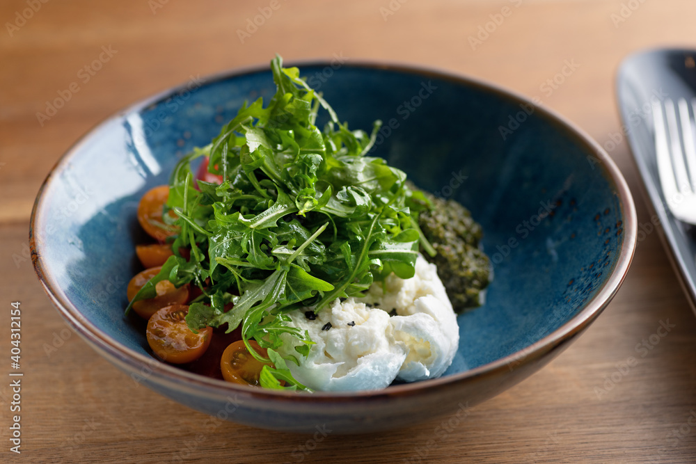 Italian fresh cheese Burrata with colorful cherry tomato salad, arugula and basil with pesto sauce Italian fresh cheese Burrata with colorful cherry tomato salad, arugula and basil with pesto sauce
