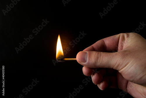 burning match with flame in hand on isolated on black background photo