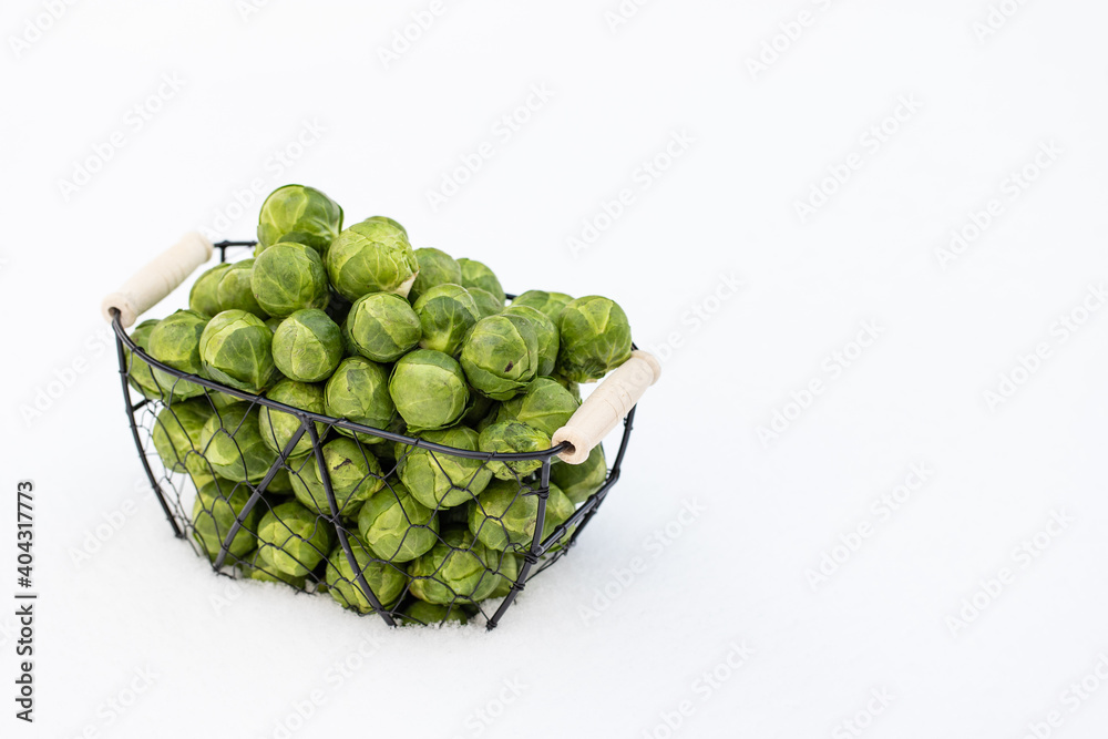 Fototapeta premium grüner Rosenkohl im Korb auf Schnee im Winter