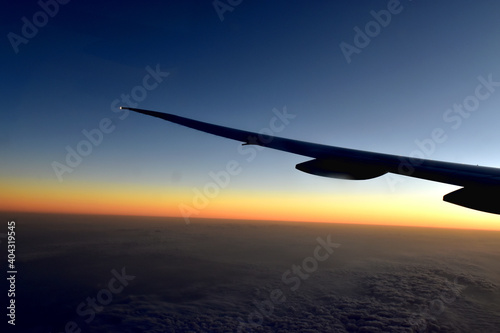 Silhouette of Airplan wing in twilight sky, with beautiful light from dramatic sunset, Romantic view from airplane window. © Eddy