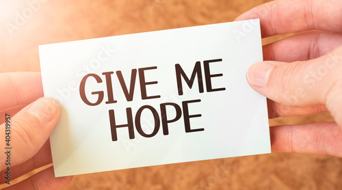 GIVE ME HOPE word inscription on white card paper sheet in hands of a businessman. recap concept. red and white paper