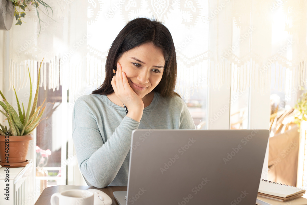 young beautiful woman looking at computer and smiling at home. Home office concept young beautiful woman looking at computer and smiling at home. Home office concept