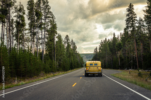 Yellow old american car on road in forest at cloudy day