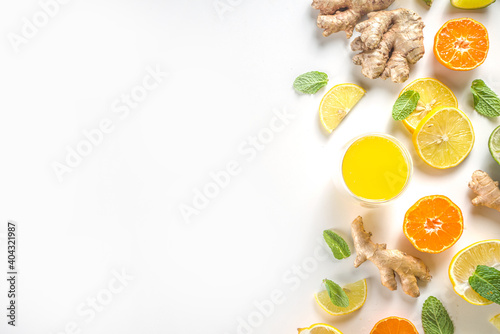 Immunity booster drink ingredients. Homemade ginger and citrus juice or cocktail, with fresh citrus fruit - orange, lemon, lime, with ginger root and mint leaves. White background top view copy space