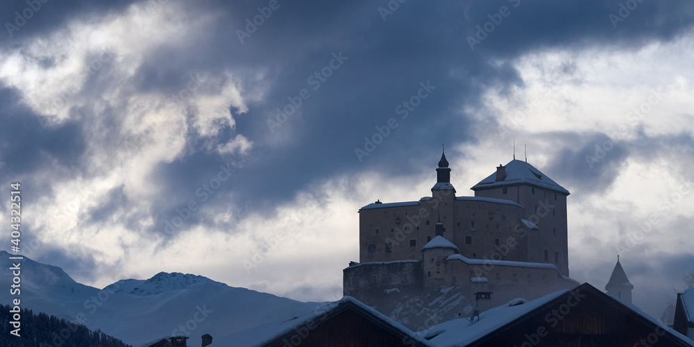 Dramatic clouds over the castle of Tarasp in the Engadin region in Switzerland before sunset.