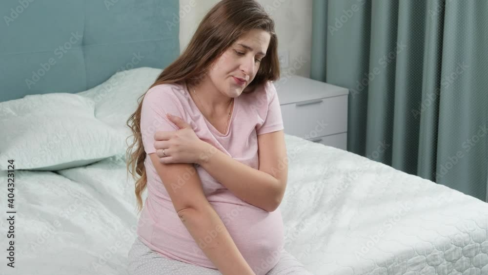 Portrait of sad and upset woman suffering from depression sitting on bed and looking out of window. Concept of maternal and pregnancy depression. Portrait of sad and upset woman suffering from depression sitting on bed and looking out of window. Concept of maternal and pregnancy depression.