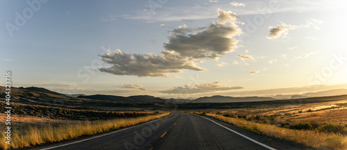 Panorama shot of road goes in wavy american nature at incoming sunset © AllThings