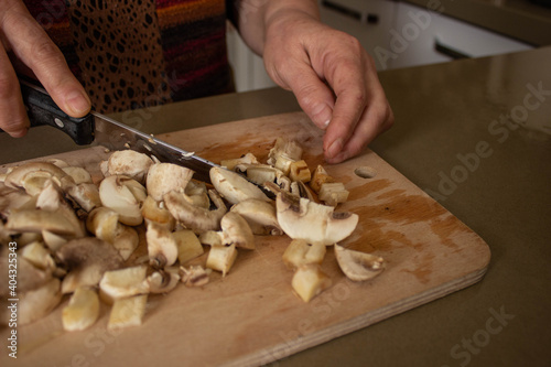 top view, woman's hand is cutting the mushrooms on the cutting board, slicing the mushrooms in kitchen.selective focus.